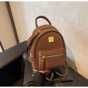 Detail view of brown woven texture backpack with golden metal zippers and decorative studs