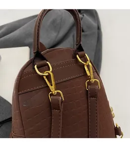 Close-up of brown crocodile texture backpack featuring gold D-rings and metal hardware details