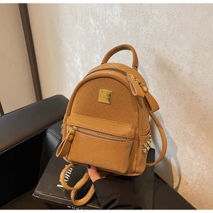 Macro view of a mini camel woven leather backpack showing golden hardware and fine texture