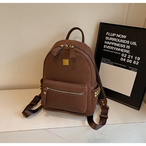 Close-up of woven texture dark brown backpack with gold logo plate and side rivets