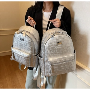 Detailed comparison of large and small silver crocodile pattern backpacks in soft leather