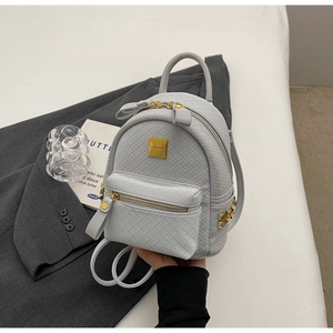 Detail of grey mini backpack with woven texture, gold studs, and top handle