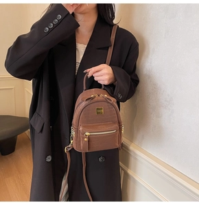 Close-up of brown crocodile pattern backpack with bow detail and gold hardware