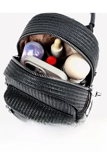 Detail view of woven straw backpack with silver zipper showing interior storage space