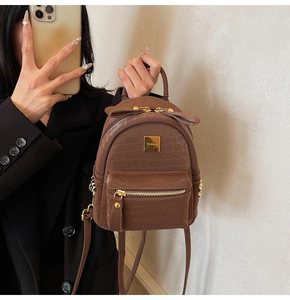 Detail of dark brown stone textured mini backpack with gold zippers and brand logo