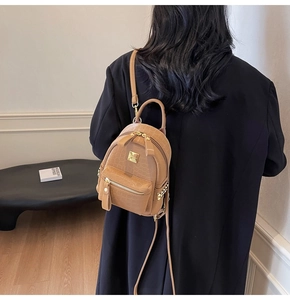 Detail of tan crocodile embossed mini backpack featuring golden hardware and side rivets