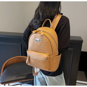 Close-up of brown crocodile texture backpack with adjustable straps and front zip pocket