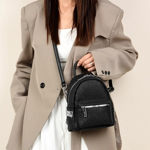Detail of black woven texture backpack with silver rivets worn by a model in urban style