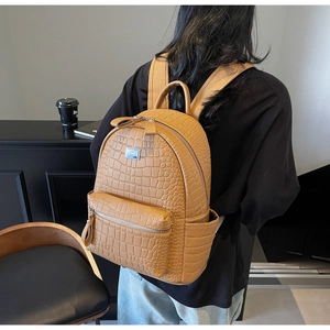 Close-up of yellow faux crocodile leather texture and front pocket on stylish backpack