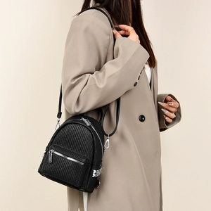Detail of woven black leather mini backpack with silver metal zipper and adjustable straps