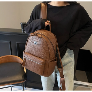 Detail of dark brown faux crocodile leather backpack showing texture and side pockets