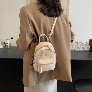 Mini cream woven leather backpack with gold hardware shown as a crossbody style bag