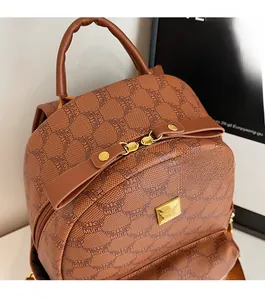 Detailed close-up of brown backpack featuring golden double zippers and MUCK monogram pattern