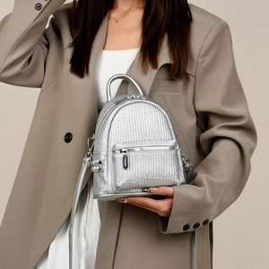 Detail of silver woven mini backpack featuring metal studs and polished hardware finish