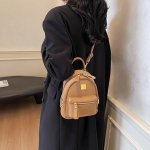 Brown woven leather mini backpack with gold logo and studs in a high-end indoor setting