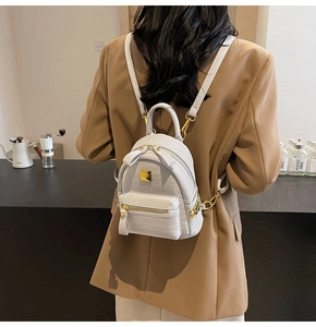 Detail view of mini faux crocodile leather backpack with gold hardware on a model
