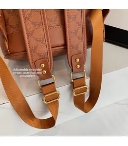 Detail of adjustable nylon shoulder straps with gold-tone hardware on a monogrammed backpack