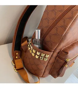 Detail of side pocket with golden studs and monogram pattern on brown backpack