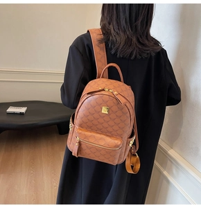 Side view of a brown monogram backpack with gold studs shown on model in a studio