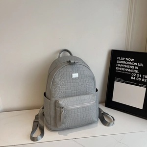 Close-up of grey crocodile texture leather backpack with silver logo and metal zippers