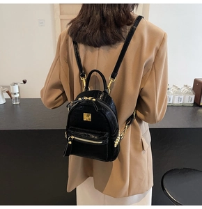 Detail of black crocodile texture mini backpack with shiny gold hardware and metal plaque