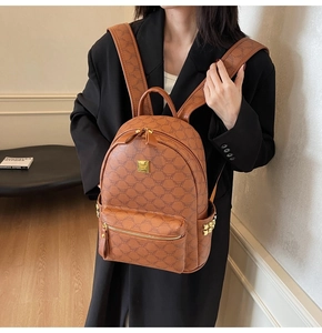 Detail view of brown monogram backpack featuring gold studs and brand plaque