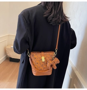 Brown bucket bag with bear print featuring a leather top handle and cute dog charm detail