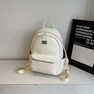 Detail view of white crocodile pattern PU leather backpack with gold logo and side pocket