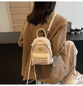 Close-up of beige crocodile pattern mini backpack with gold hardware and fine straps