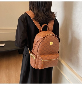 Detailed back view of a brown backpack featuring logo print and gold pyramid studs