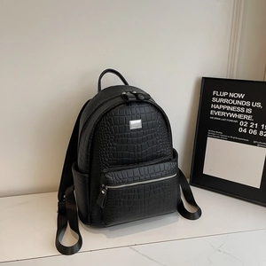 Detail of black faux leather backpack featuring crocodile embossed texture and front zipper