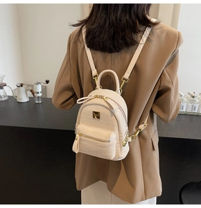 Detail of stone pattern texture and gold hardware on a cream beige mini backpack