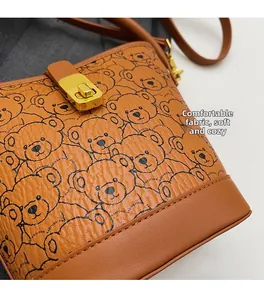 Close-up of brown bucket bag with teddy bear print and golden twist lock closure
