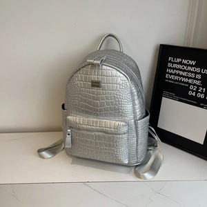 Detail of silver crocodile-pattern leather backpack with metal logo and multi-pocket design