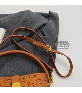 Detail of bear print brown bucket bag with adjustable shoulder strap and gold hardware