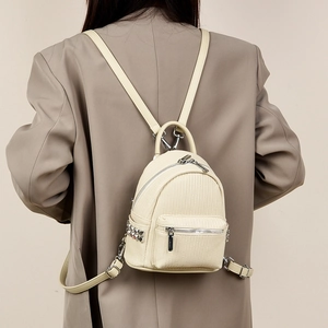 Model view of cream mini backpack with woven texture and silver metal hardware details