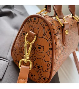 Detail of premium golden hardware and bear print texture on a brown barrel bag