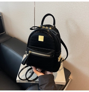 Detail of black faux leather mini backpack with crocodile texture and gold-tone hardware