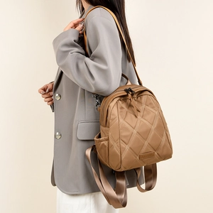 Side view of a brown quilted backpack featuring diamond stitching and adjustable straps