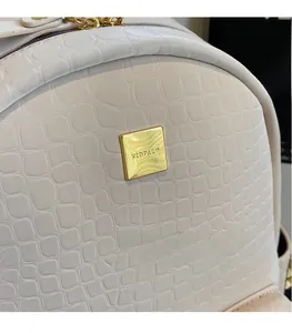 Detailed macro view of white crocodile pattern leather texture and golden square metal logo