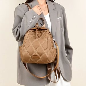 Close-up of brown quilted diamond pattern backpack with leather logo tag and nylon straps
