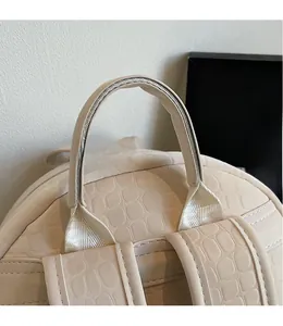 Detail view of beige faux leather backpack with crocodile texture and sturdy top handle