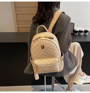 Detail view of monogram cream leather backpack featuring golden hardware and MUGE branding