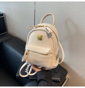 Detail view of mini off-white crocodile textured backpack with gold VISFAL metal logo
