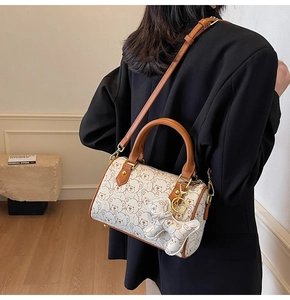 Detail of Boston bag showing cute bear print, gold hardware, and bear charm accessory
