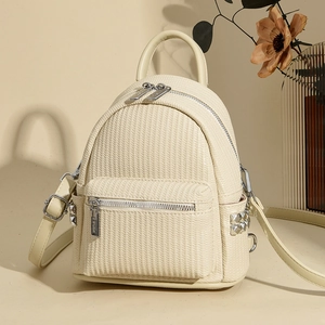 Detail of cream woven leather mini backpack featuring silver studs and top handle