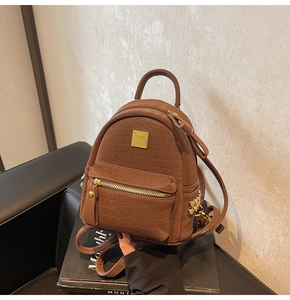 Detail of a brown faux crocodile leather backpack with gold zippers and metal hardware