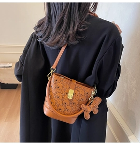 Detail of a brown leather shoulder bag featuring all-over cartoon bear patterns and gold clasp