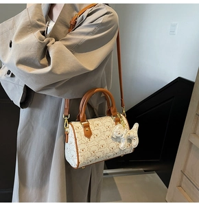 Detailed view of cream barrel bag with bear prints, leather straps and puppy charm