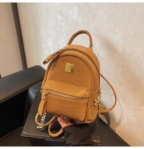 Close-up of brown crocodile texture backpack with gold studs and square logo plate